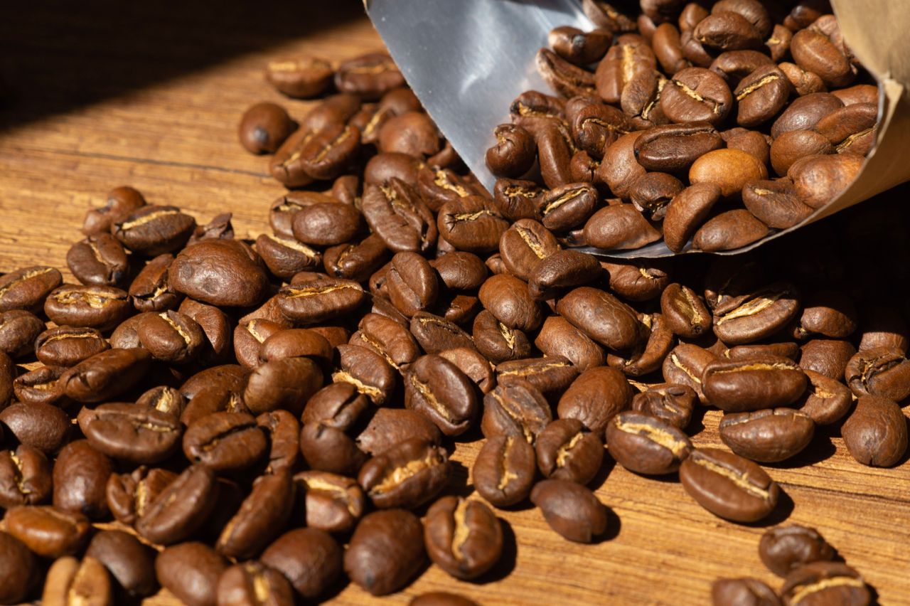 Close-up of aromatic roasted coffee beans spilling from a bag onto wooden surface in Arnavutköy, Istanbul.