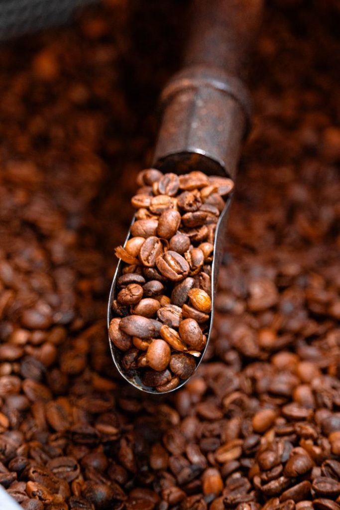 A detailed view of a scoop filled with aromatic roasted coffee beans, showcasing rich textures.